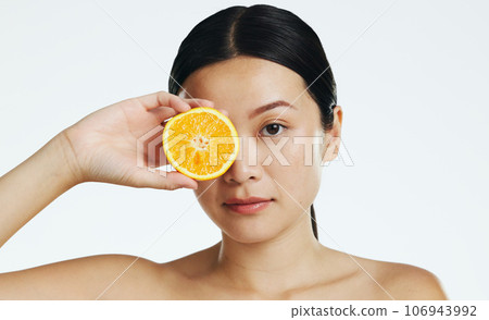 Orange fruits, skincare and face of woman in studio, white background and cosmetics. Beauty model, asian female and portrait of citrus for vitamin c, natural detox and healthy aesthetic dermatology 106943992