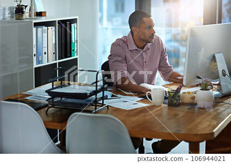 African businessman, office and reading at computer, focus and planning with vision, goal and start morning with ideas. Corporate black man, pc and notebook for strategy, typing or email on internet 106944021