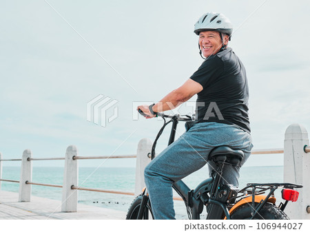 Electric bike, portrait or travel with a senior man on a promenade, riding eco friendly transport by the beach. Sustainability, cycling or mock up with a mature male tourist by the seaside for a ride Electric bike, portrait or travel with a senior man on a promenade, riding eco friendly transport by the beach. Sustainability, cycling or mock up with a mature male tourist by the seaside for a ride 106944027