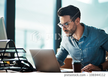 Serious, business man and laptop in office for planning, online research or developer reading data at desk. Focused worker, computer and website connection for digital project, internet or technology 106944112