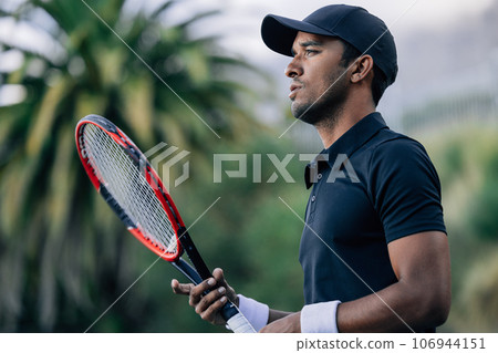 Side view of a young tennis player with racket looking away Side view of a young tennis player with racket looking away 106944151