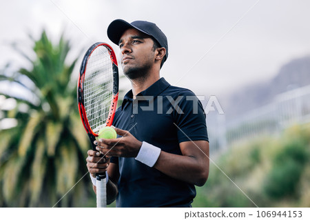 Young tennis player with racket standing outdoors Young tennis player with racket standing outdoors 106944153