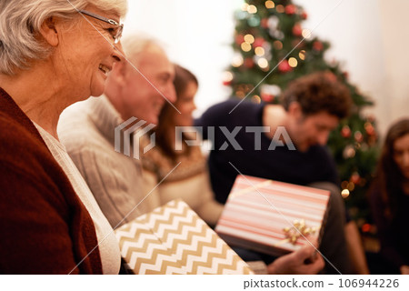 Christmas, gift and happy with family in living room for celebration, festive and holiday. Smile, party and gratitude with old woman and present with children at home for giving, event and tradition 106944226