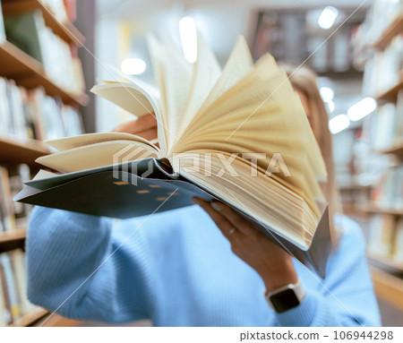 Education, book and pages in a library for reading for knowledge, learning or studying. Information, books and woman looking at paper in a novel or story at a book store to study, learn or read. 106944298