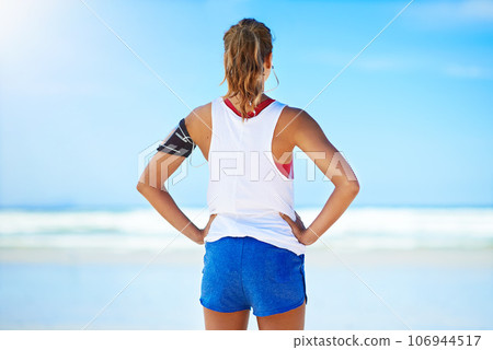 Fitness, woman runner and relax on a break at the beach for exercise, workout or training in the outdoors. Active healthy female relaxing or breathing after running or exercising by the ocean coast Fitness, woman runner and relax on a break at the beach for exercise, workout or training in the outdoors. Active healthy female relaxing or breathing after running or exercising by the ocean coast 106944517