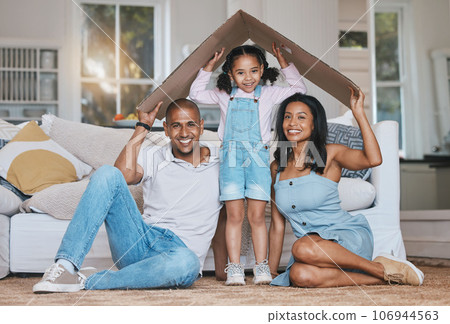 Portrait, cardboard roof and family in the lounge, home insurance and care with protection, smile and safety. Face, parents or mother with father, girl and daughter in the living room, love and cover 106944563