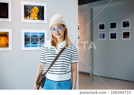 Visitor woman smiling on art gallery collection in front framed paintings pictures on white wall, lifestyle Asian people watch at photo frame to leaning against at show exhibition artwork gallery Visitor woman smiling on art gallery collection in front framed paintings pictures on white wall, lifestyle Asian people watch at photo frame to leaning against at show exhibition artwork gallery 106944710