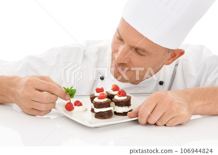 Baking, presentation and chef with a dessert for catering isolated on a white background. Cooking, professional and man plating a chocolate cake and fruit on a plate for service on a backdrop Baking, presentation and chef with a dessert for catering isolated on a white background. Cooking, professional and man plating a chocolate cake and fruit on a plate for service on a backdrop 106944824