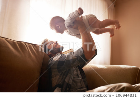 Dad, funny and lifting baby on sofa in home living room, playing or bonding together. Laughing, care and father holding infant, newborn or child on couch in lounge, having fun and enjoying time. Dad, funny and lifting baby on sofa in home living room, playing or bonding together. Laughing, care and father holding infant, newborn or child on couch in lounge, having fun and enjoying time. 106944831