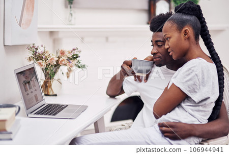 My test results should pop up anytime now...Shot of a young couple using a laptop while sitting together at home. My test results should pop up anytime now...Shot of a young couple using a laptop while sitting together at home. 106944941
