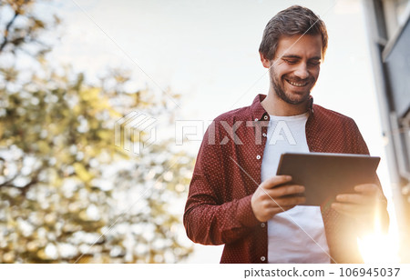 Always online, always connected. Cropped shot of a handsome young man using his digital tablet outside. Always online, always connected. Cropped shot of a handsome young man using his digital tablet outside. 106945037