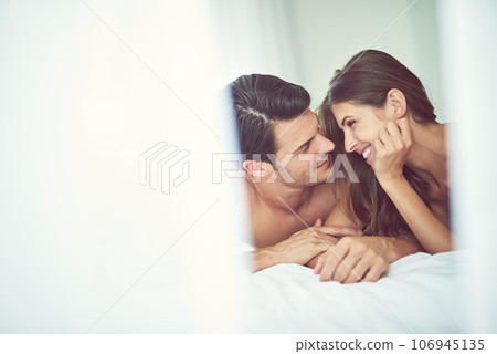 With you is a beautiful place to be. Cropped shot of a young couple relaxing in their bedroom. With you is a beautiful place to be. Cropped shot of a young couple relaxing in their bedroom. 106945135