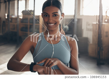Woman, gym portrait and point at watch, fitness or schedule for workout, training or wellness. Indian girl, personal trainer and time for exercise with smile, music or audio streaming subscription 106945153