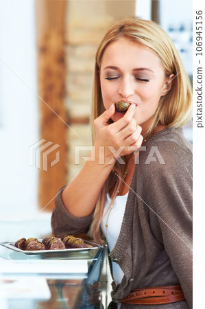 Mmmmmm, this tastes amazing. Pretty young woman biting in to a sample chocolate at the shops. 106945156