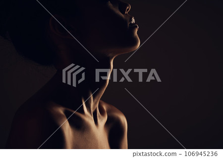 Beauty, woman and silhouette dark background of skin, body and model with glow, light and art on black. Face of aesthetic model person in studio for abstract, creativity and shadow profile or space 106945236