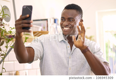 Saying hi from over here. Shot of a young man on a video call at home. 106945309