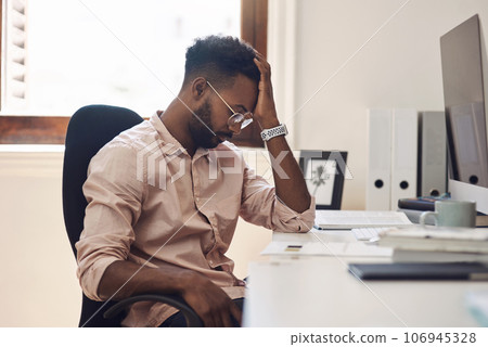 Facing a tough challenge in his workday. Shot of a young businessman looking tired while working in an office. Facing a tough challenge in his workday. Shot of a young businessman looking tired while working in an office. 106945328