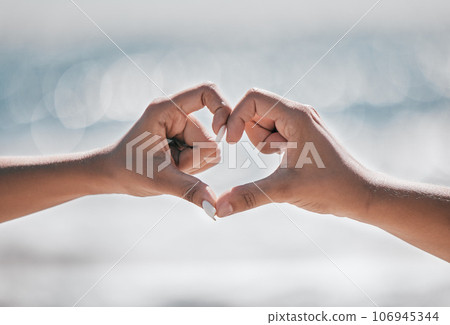 Hands, heart and couple with love, peace and unity sign on mockup, space or blurred background. Hand, emoji and finger shape by man and woman at a beach for travel, vacation or summer trip in Bali 106945344