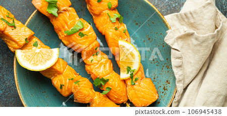 Grilled barbecue salmon skewers seasoned with green parsley and lemon on ceramic plate on dark blue concrete rustic table background top view, healthy eating 106945438