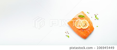 Fresh raw salmon marbled fillet isolated on white background with lemon, coarse salt, green herbs top view. Healthy nutrition and balanced diet 106945449