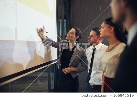Getting her team involved in the business process. Shot of an executive giving a presentation on a projection screen to a group of colleagues in a boardroom. 106945519