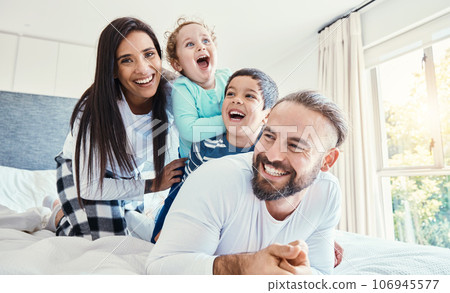 Portrait, family and laughing on bed in home, having fun and bonding together. Comic, love and care of happy father, mother and kids or boys playing, smile and enjoying quality time in house bedroom. 106945577