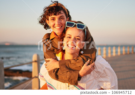 Lesbian, portrait and couple of friends at the beach in piggyback, support and happy for lgbtq love. Sunset, sea and smile of women or gay people on summer date with pride, freedom and gen z holiday Lesbian, portrait and couple of friends at the beach in piggyback, support and happy for lgbtq love. Sunset, sea and smile of women or gay people on summer date with pride, freedom and gen z holiday 106945712