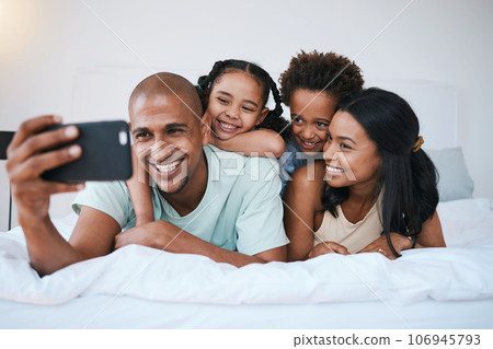 Selfie, family and smile in home bedroom, bonding and relaxing or lying together. Bed, photo and children with mother and father taking pictures for happy memory, social media or profile picture. Selfie, family and smile in home bedroom, bonding and relaxing or lying together. Bed, photo and children with mother and father taking pictures for happy memory, social media or profile picture. 106945793