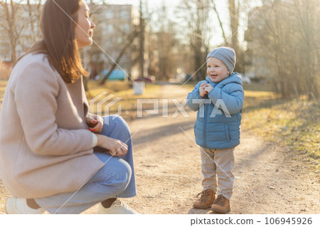 Happy family outdoor. Mother child on walk in park. Mom playing with baby son outdoor. Woman little baby boy resting walking in nature. Little toddler child and babysitter nanny having fun together Happy family outdoor. Mother child on walk in park. Mom playing with baby son outdoor. Woman little baby boy resting walking in nature. Little toddler child and babysitter nanny having fun together 106945926