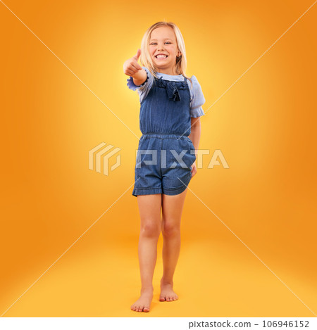 Happy, portrait of child and thumbs up in studio for support, like emoji or yes approval. Excited girl kid on orange background or space for hand gesture, barefoot or sign for agreement or thank you Happy, portrait of child and thumbs up in studio for support, like emoji or yes approval. Excited girl kid on orange background or space for hand gesture, barefoot or sign for agreement or thank you 106946152