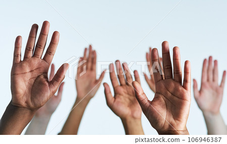Raise your hands as one. Shot of a group of hands reaching up against a white background. Raise your hands as one. Shot of a group of hands reaching up against a white background. 106946387