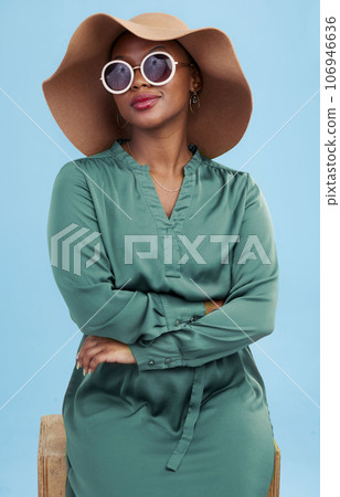 Fashion, sunglasses and portrait of black woman with cool style for summer isolated in a studio blue background. African, hat and young person travel with clothes for glamour or luxury accessories Fashion, sunglasses and portrait of black woman with cool style for summer isolated in a studio blue background. African, hat and young person travel with clothes for glamour or luxury accessories 106946636