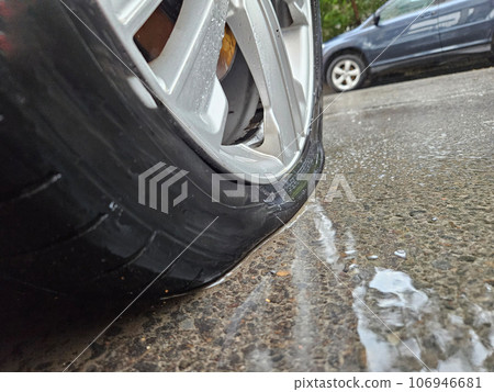 On a wet asphalt road, one of the tires is completely flat On a wet asphalt road, one of the tires is completely flat 106946681