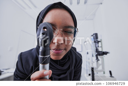 Vision, optometrist and woman with retinoscope in hospital for examination. Eye test, healthcare and muslim doctor or ophthalmologist with equipment tool for eyecare, health and wellness in clinic. 106946729