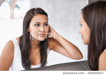 Getting excited for her date. A cropped shot of a beautiful young woman deciding on a hair style in front of her bathroom mirror. 106946935