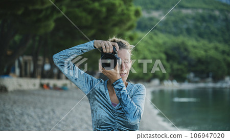 Front view of a young woman taking a photo directly at the camera 106947020