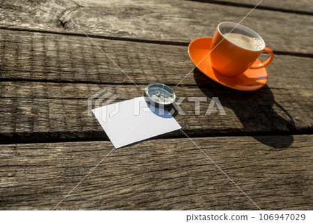 Blank paper with compass next to orange cup of coffee Blank paper with compass next to orange cup of coffee 106947029