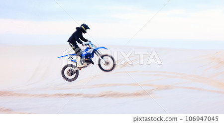 Sand, jump or athlete driving motorcycle for fitness, adventure or action with performance or adrenaline. Desert, risk or sports person on motorbike on dunes for training, exercise or race challenge 106947045