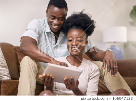 Would you look at this. Shot of a young couple using a digital tablet together at home. 106947128