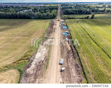 High angle view of a road construction project cutting through an agricultural district of farm fields. High angle view of a road construction project cutting through an agricultural district of farm fields. 106947148