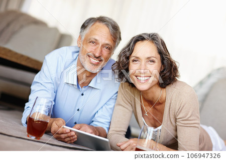 Spontaneity is the spice of life. Portrait of a happy mature couple lying on the floor and using a digital tablet. Spontaneity is the spice of life. Portrait of a happy mature couple lying on the floor and using a digital tablet. 106947326