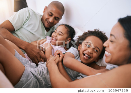 Happy family, relax and playing in bed with smile for free time, weekend or fun holiday morning at home. Mother, father and children relaxing and laughing together for playful joy in the bedroom Happy family, relax and playing in bed with smile for free time, weekend or fun holiday morning at home. Mother, father and children relaxing and laughing together for playful joy in the bedroom 106947339