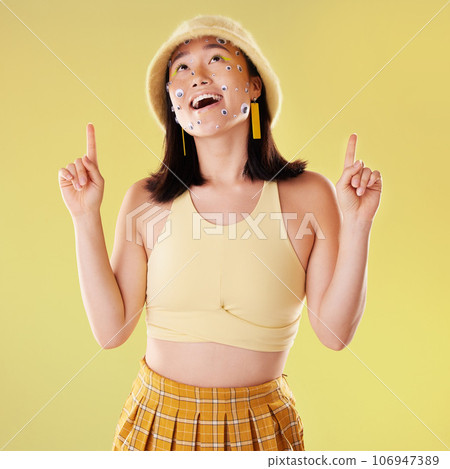 Thinking, pointing and woman with eyes for comedy isolated on a yellow background in a studio. Idea, comic and Asian girl with a gesture up and facial product for expression and funny on a backdrop Thinking, pointing and woman with eyes for comedy isolated on a yellow background in a studio. Idea, comic and Asian girl with a gesture up and facial product for expression and funny on a backdrop 106947389