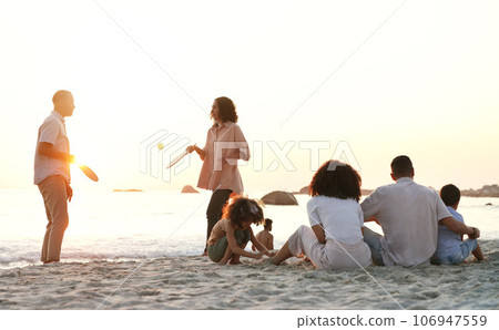 Travel, game and family at the beach on a summer vacation, adventure or weekend trip in Australia. Sunset, fun and people playing sports on the sand by the ocean on seaside holiday together. 106947559