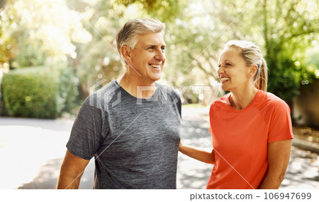 Happy mature couple keeping active, fit and healthy while jogging, running or going for walk outdoors in nature environment. Laughing senior man and woman enjoying a break from workout or exercising Happy mature couple keeping active, fit and healthy while jogging, running or going for walk outdoors in nature environment. Laughing senior man and woman enjoying a break from workout or exercising 106947699