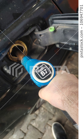 Manually refueling the car with fuel at the gas station Manually refueling the car with fuel at the gas station 106947701