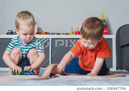 Two children boy play together with toys in interior of children's room.. 106947794