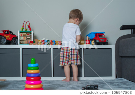 Toddler boy plays in playroom with educational toys... Toddler boy plays in playroom with educational toys... 106947808