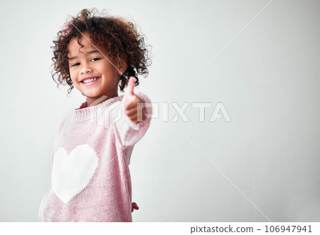 Nothing but good vibes. Shot of an adorable little girl standing alone and showing a thumbs up against a grey background. 106947941