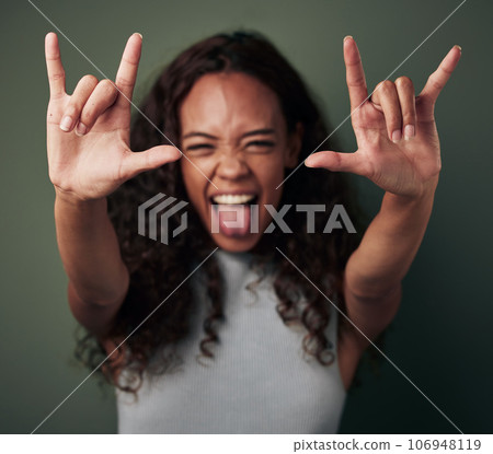 Woman, portrait and rock hand in green studio background shows tongue with emoji and crazy. Female person, rocker and gesture with hands to celebrate or winning with excited face for a party. 106948119